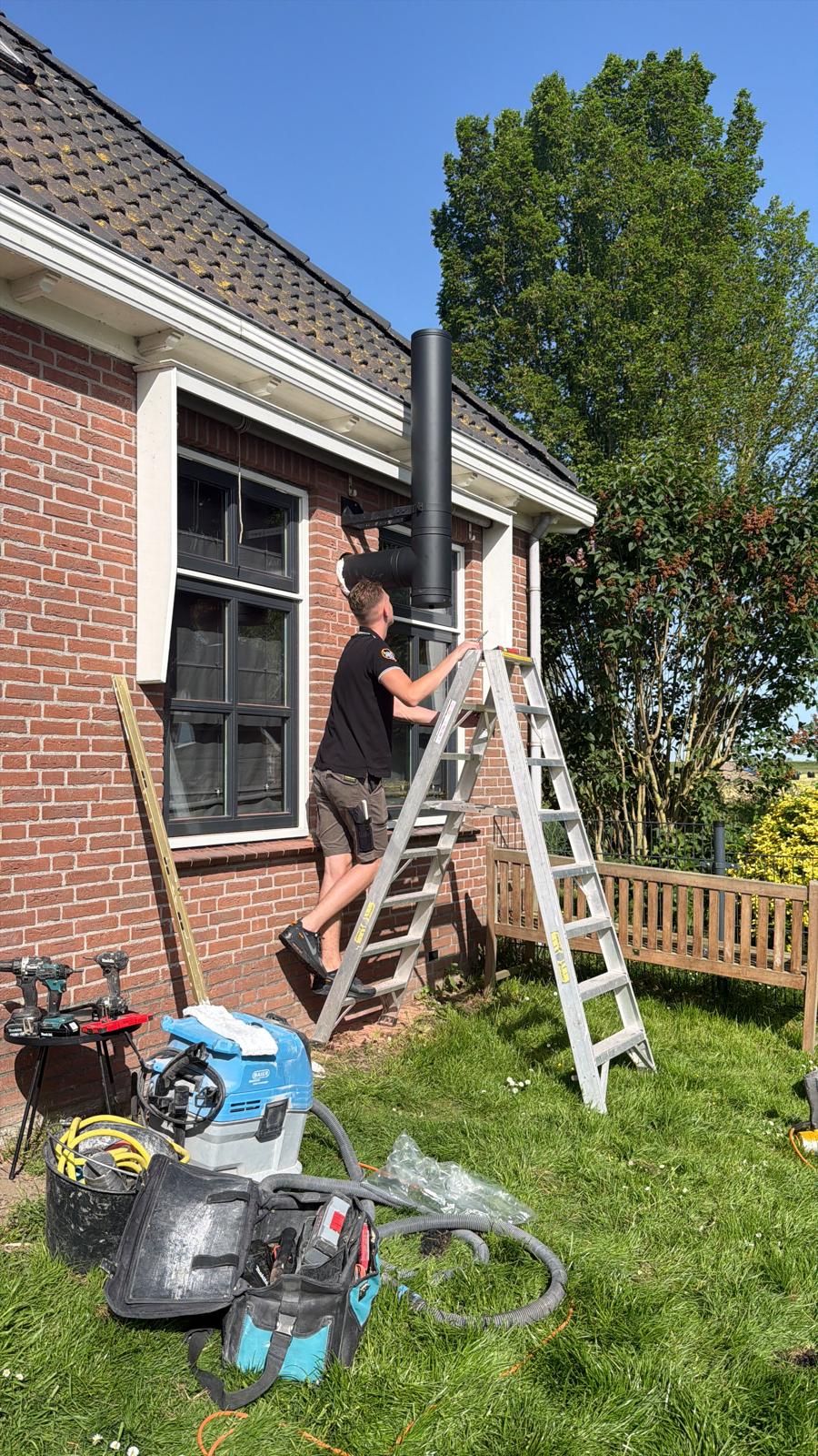 Monteur van Houtstook enzo aan het werk aan de geveldoorvoer in Wijdewormer