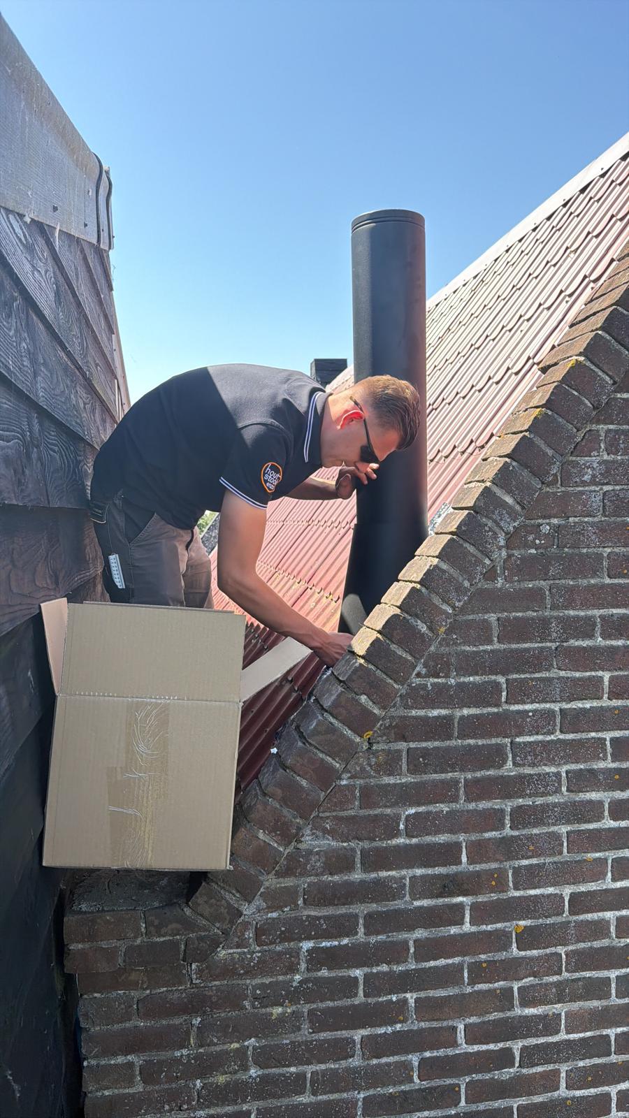 Monteur van Houtstook enzo op het dak tijdens de plaatsing van het rookkanaal in Wijdewormer