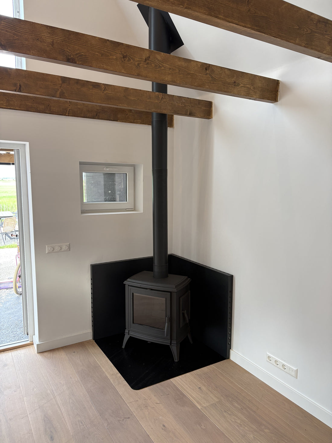 Invicta Sedan M houtkachel met warmtepanelen tegen de wand, bijwoning Wijdewormer