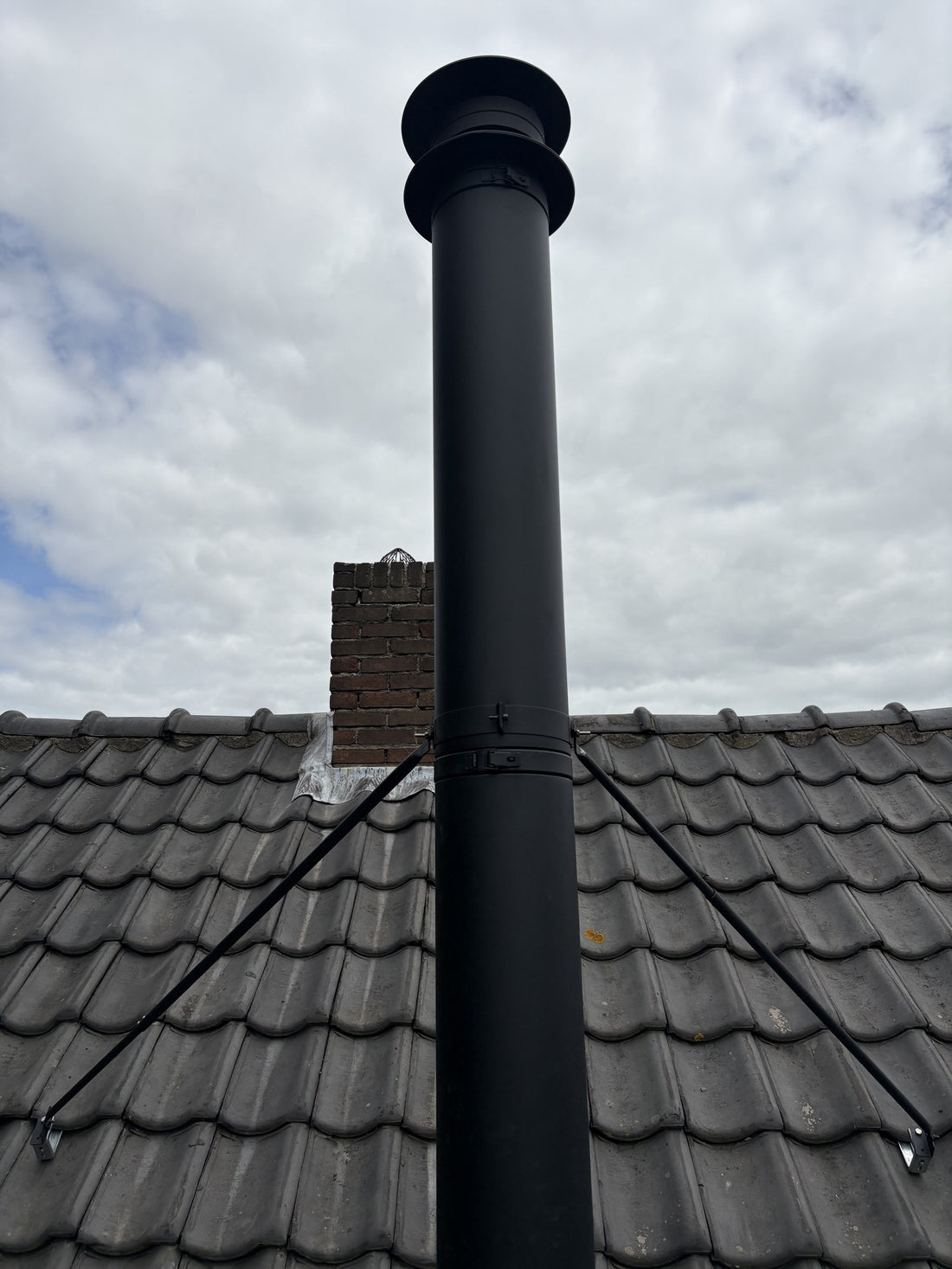 Dubbelwandig rookkanaal geschoord met tuibeugels, boven de nok van het dak